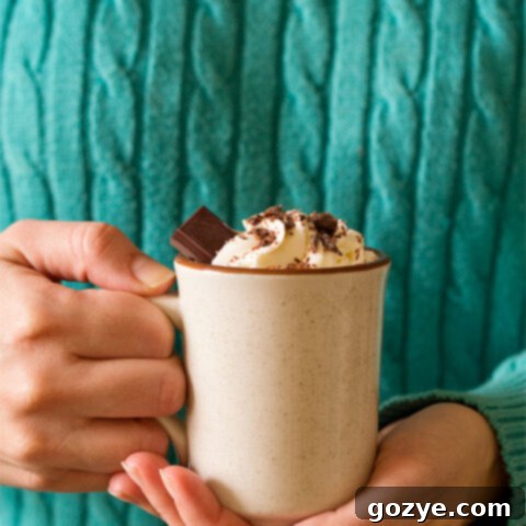 Woman in turquoise sweater holding mug of thick hot chocolate