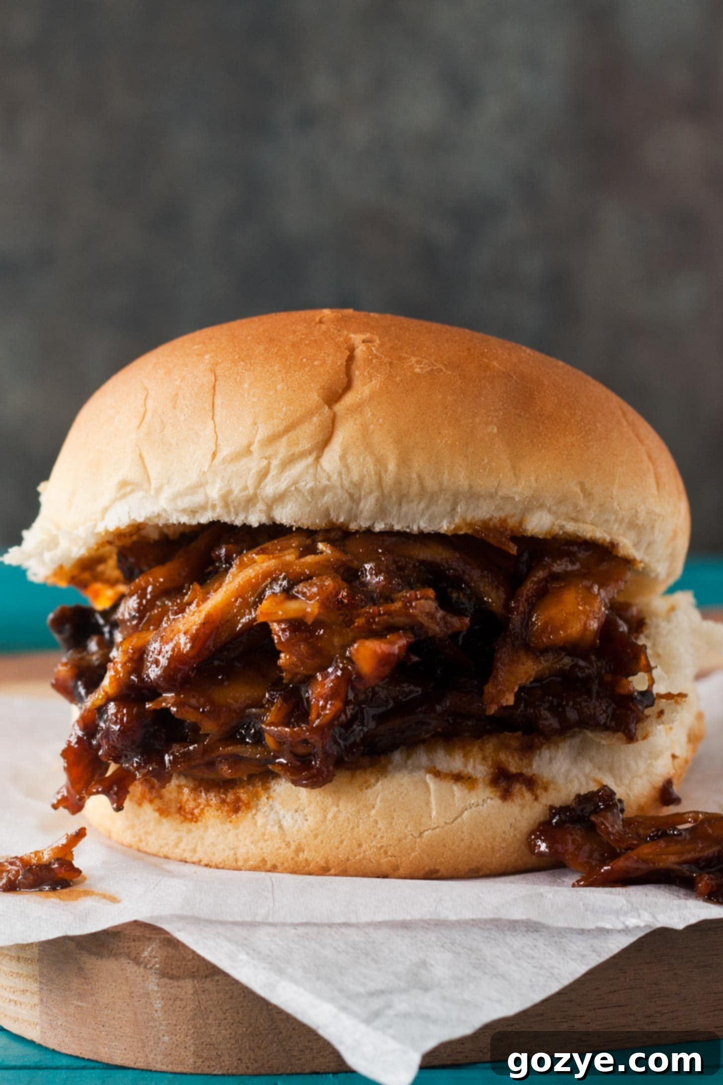 Set-It-and-Forget-It BBQ Pulled Chicken 2 Slow Cooker BBQ Pulled Chicken sandwiches on parchment paper