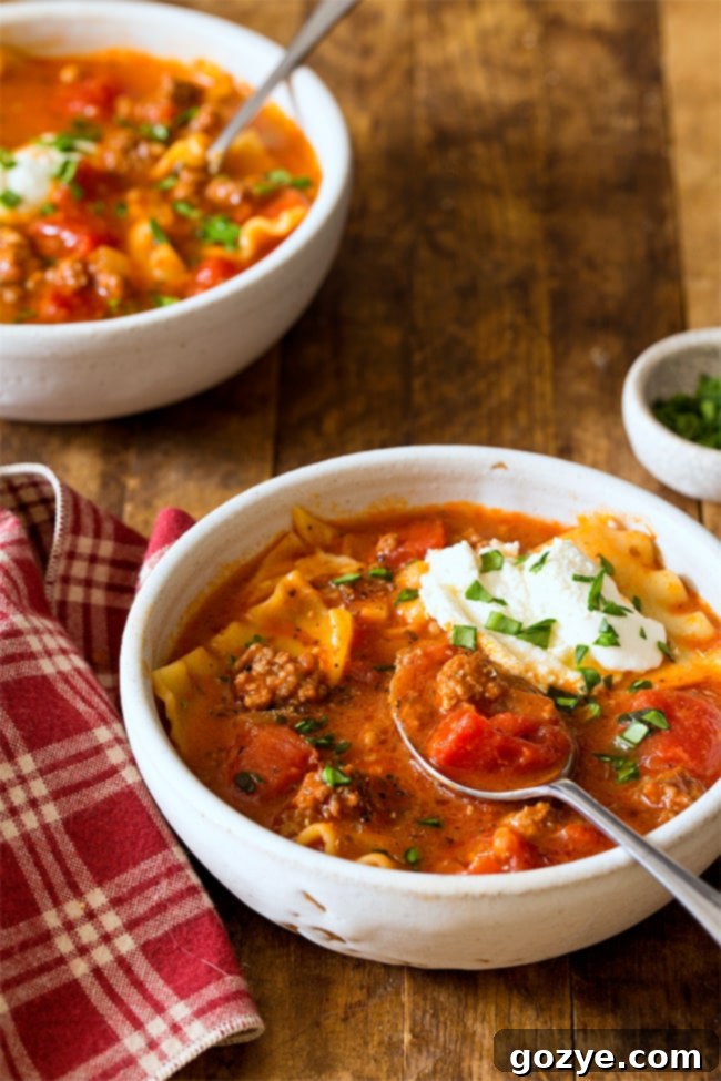 Lasagna soup in a white bowl, ready to be served, garnished with fresh basil leaves.