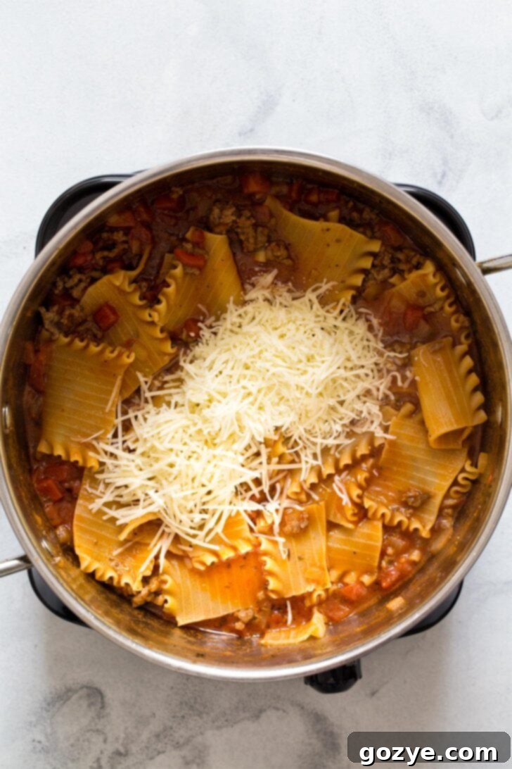 Stirring shredded mozzarella, Parmesan, and fresh basil into the finished lasagna soup.