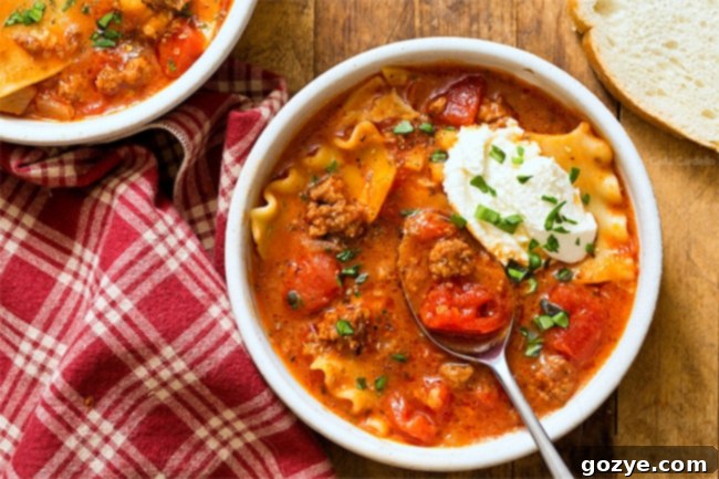 A serving of One Pot Lasagna Soup in a white bowl, garnished with fresh herbs, ready to eat.