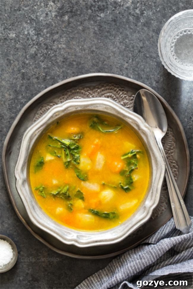 Kohlrabi Soup with Kohlrabi Greens in a silver ridged bowl on a dark gray plate