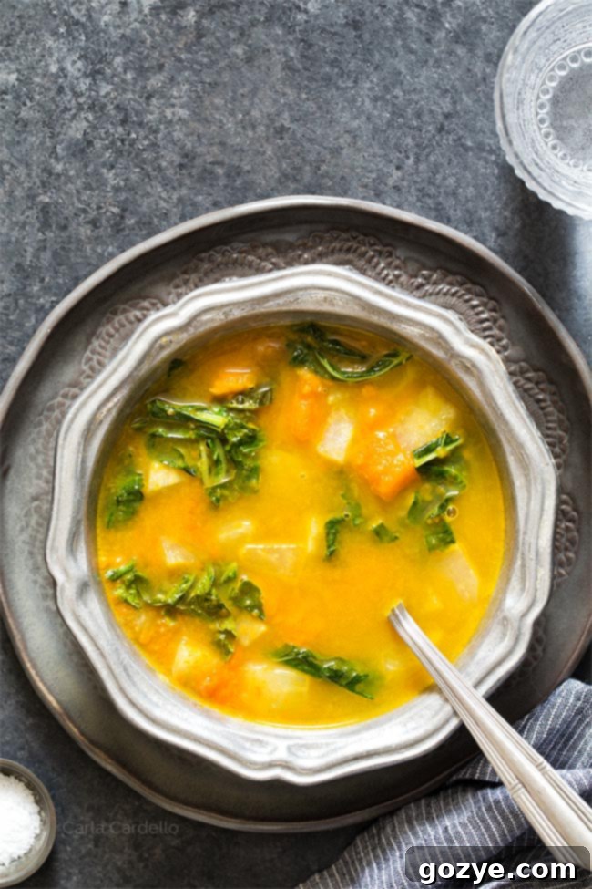 Kohlrabi Soup with Kohlrabi Greens in a silver ridged bowl on a dark gray plate