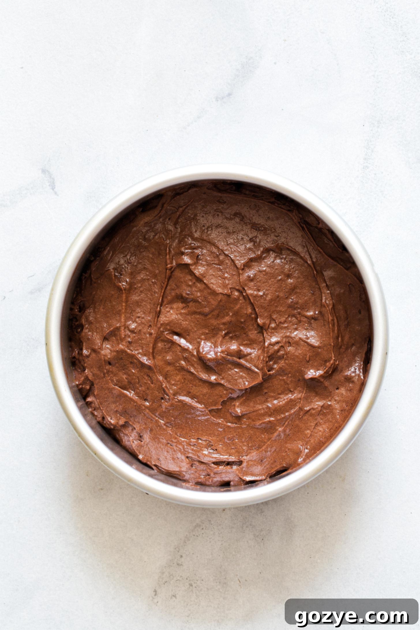 Unbaked chocolate cake batter evenly distributed in a 6-inch cake pan