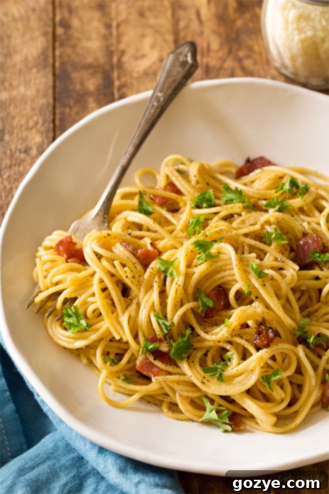Close-up of creamy Spaghetti Carbonara for Two with bacon and cheese, garnished with black pepper and fresh parsley, ready for a romantic meal.