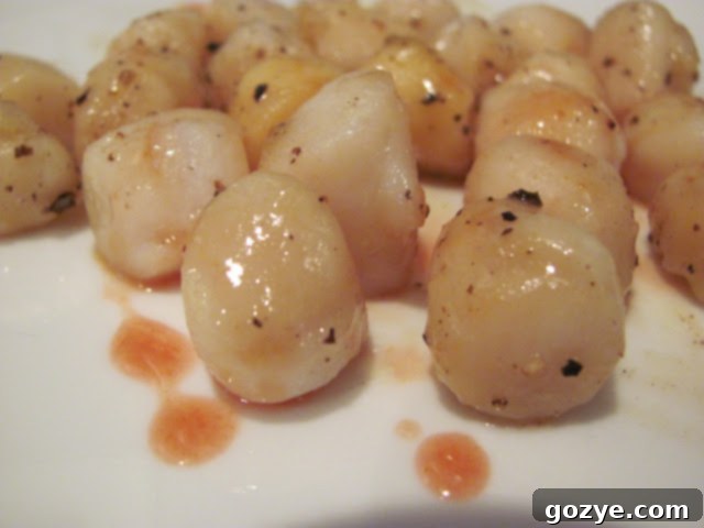 Perfectly seared scallops with a rich caramel orange sauce on a white plate, garnished with fresh herbs.