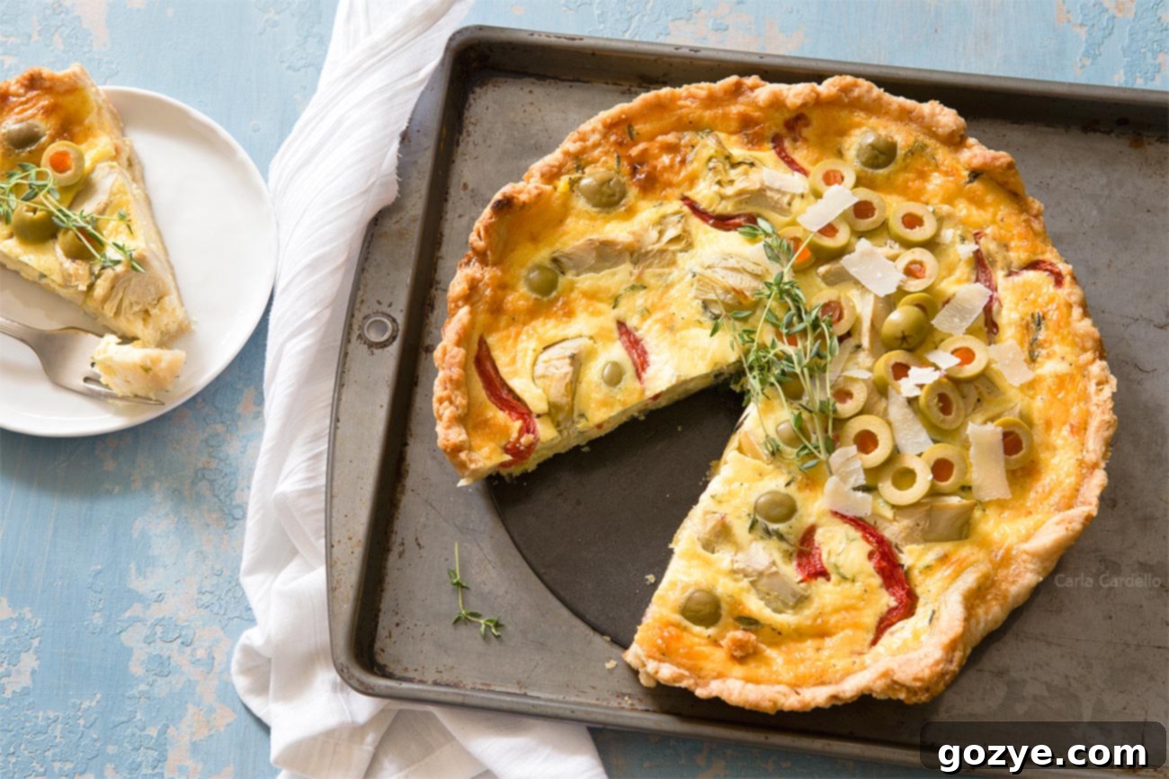 Vegetarian Artichoke Quiche with a slice removed, showing the golden crust and colorful filling.