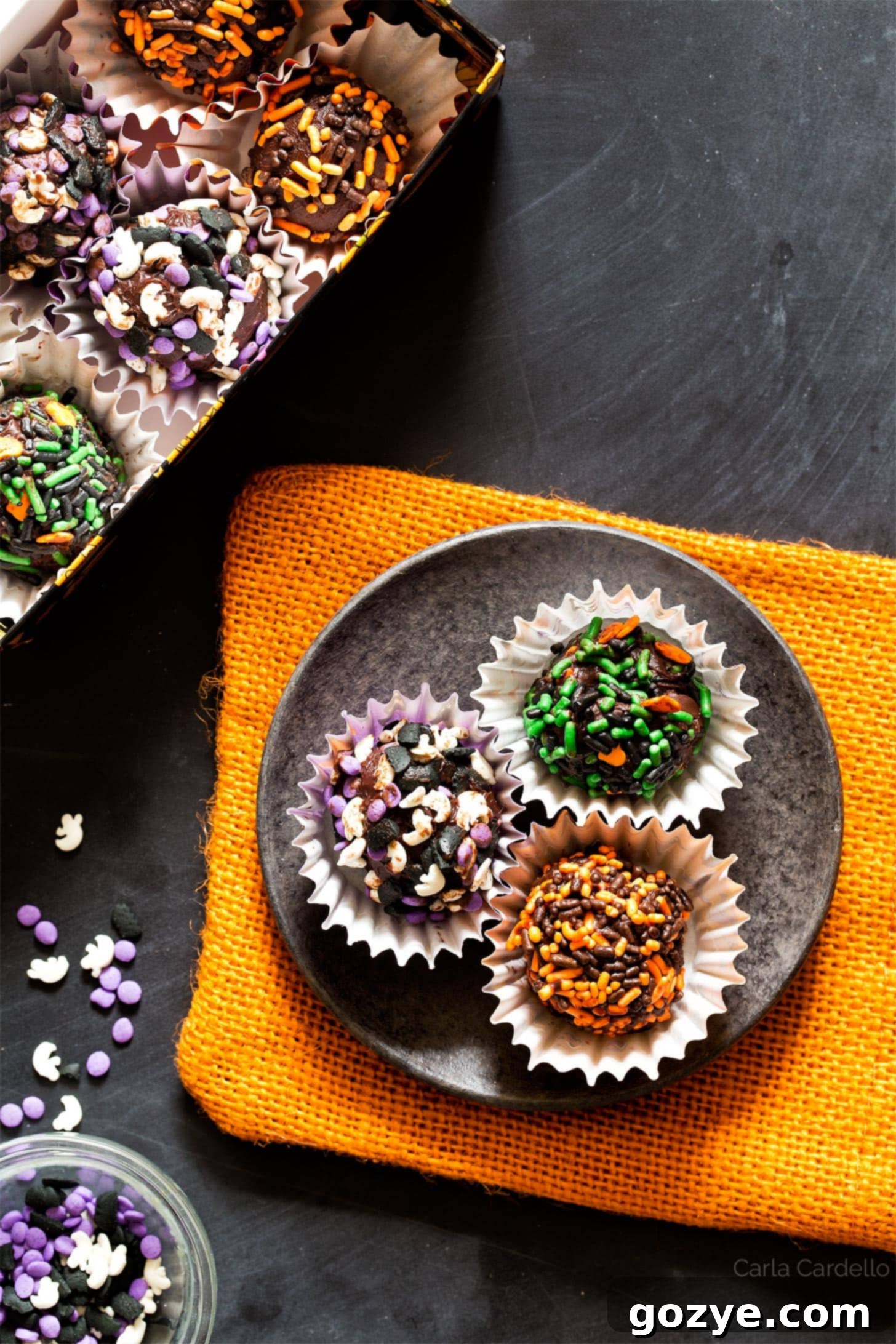 Halloween Truffles arranged beautifully on a black plate with a vibrant orange linen underneath, highlighting their spooky charm.