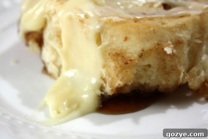 Apple Cider Cinnamon Rolls 3 Close-up of Apple Cider Cinnamon Rolls with a generous swirl of white cream cheese frosting, showing the warm, soft interior.