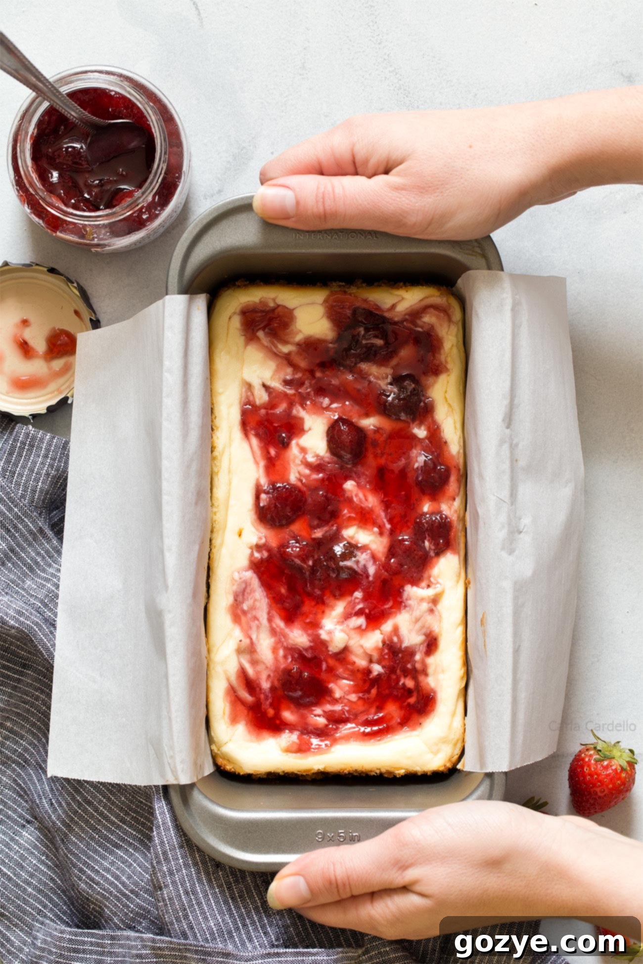 Hands removing cheesecake bars from loaf pan