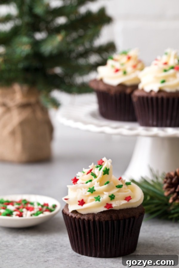 These small batch Chocolate Gingerbread Cupcakes with homemade cream cheese frosting makes a half dozen cupcakes. Ideal for when you want a small Christmas dessert without too many leftovers. A single cupcake on a white plate with a fork, ready to be eaten.