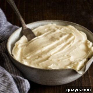 Homemade Cream Cheese Frosting in a bowl with wooden spoon