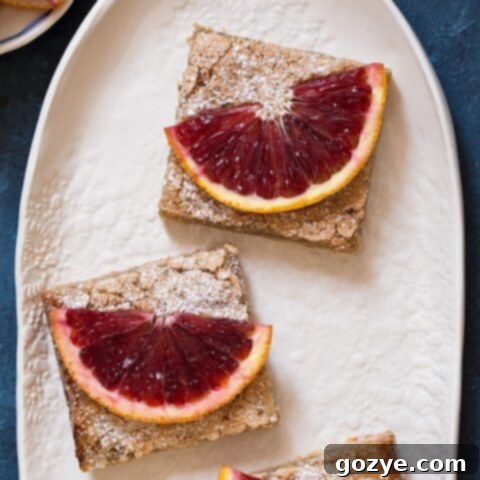 Beautifully cut small batch Blood Orange Bars, dusted with powdered sugar, arranged on a serving plate.