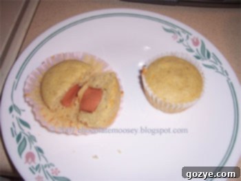 An older, less polished photograph of a single corn dog muffin on a plate, showcasing the hot dog peeking out.
