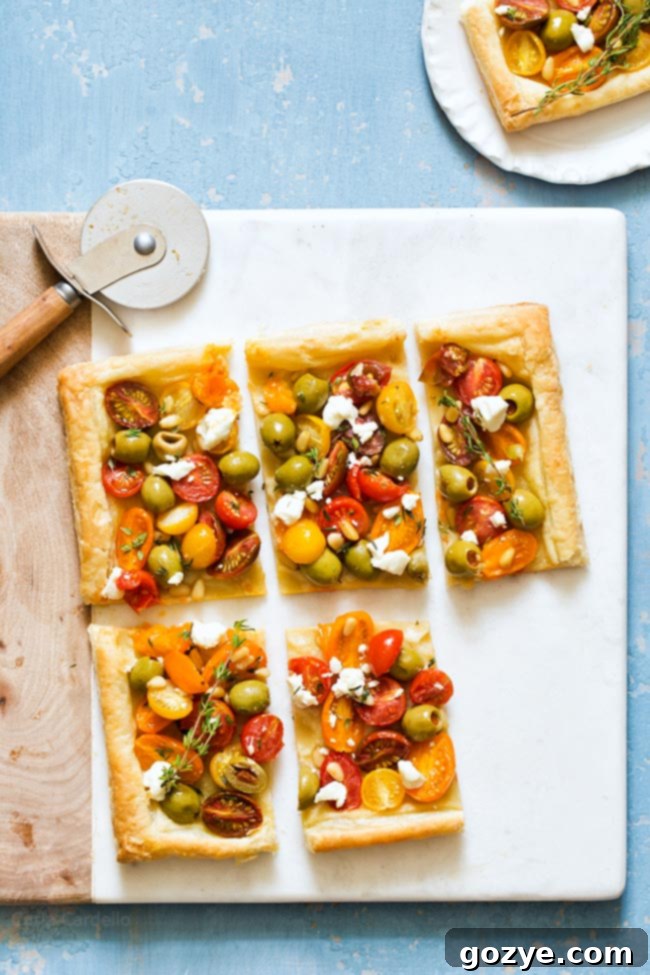 Celebrate the flavors of summer with Olive Tomato Puff Pastry Tart topped with goat cheese, thyme, and pine nuts.