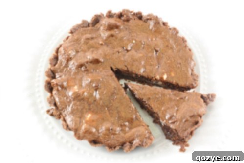 A close-up view of a baked chocolate truffle tartlet, featuring a perfectly set, dark chocolate filling within a golden-brown crust.