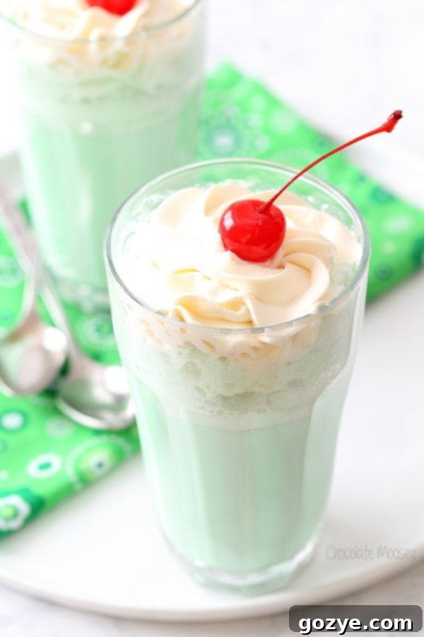Copycat McDonald's Shamrock Shake with a generous swirl of Irish Cream Whipped Cream and a maraschino cherry