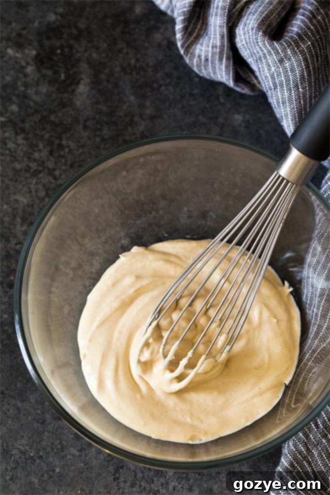 Glass bowl filled with peanut butter whipped cream, with a whisk resting inside