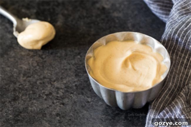 Peanut butter whipped cream served in a small silver bowl, garnished with a sprinkle of peanuts