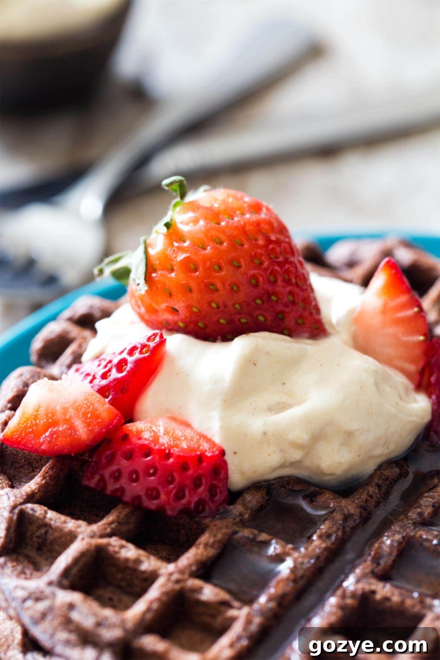 Peanut butter whipped cream dollops on a stack of chocolate waffles, drizzled with chocolate sauce