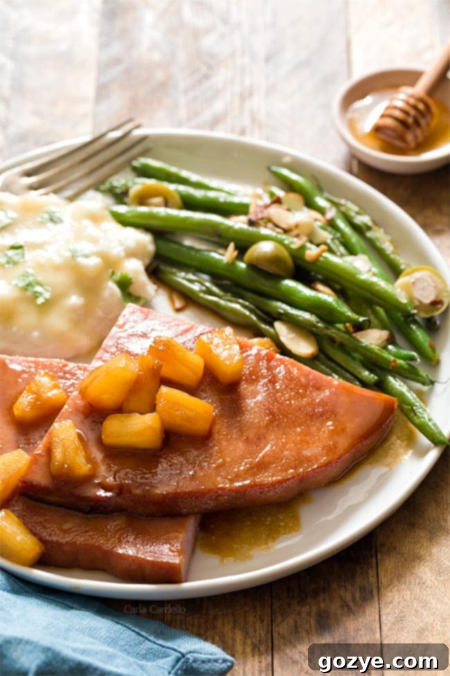 Plate of ham steak, green beans, and mashed potatoes, showcasing a complete and appealing dinner.
