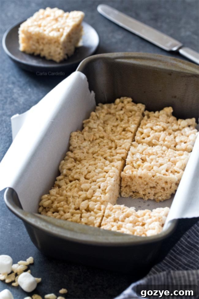 Personal Krispie Bites 3 Rice krispie treats in a loaf pan with a square cut out, showing the gooey texture