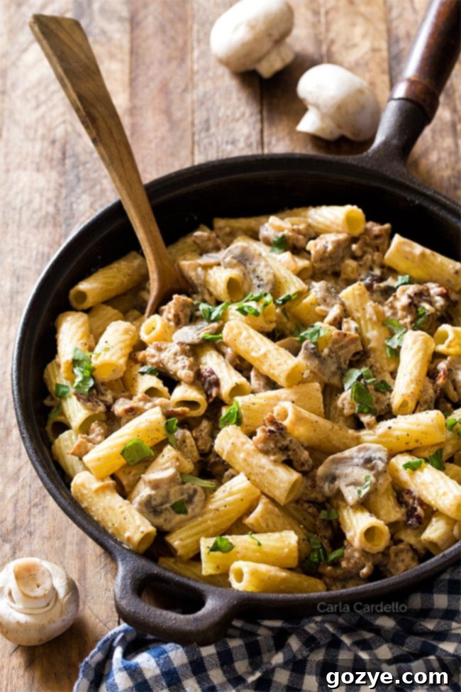 Sausage Mushroom Pasta in cast iron pan with wooden spoon