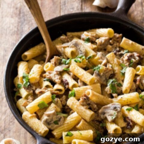 Sausage Mushroom Pasta in cast iron pan with wooden spoon
