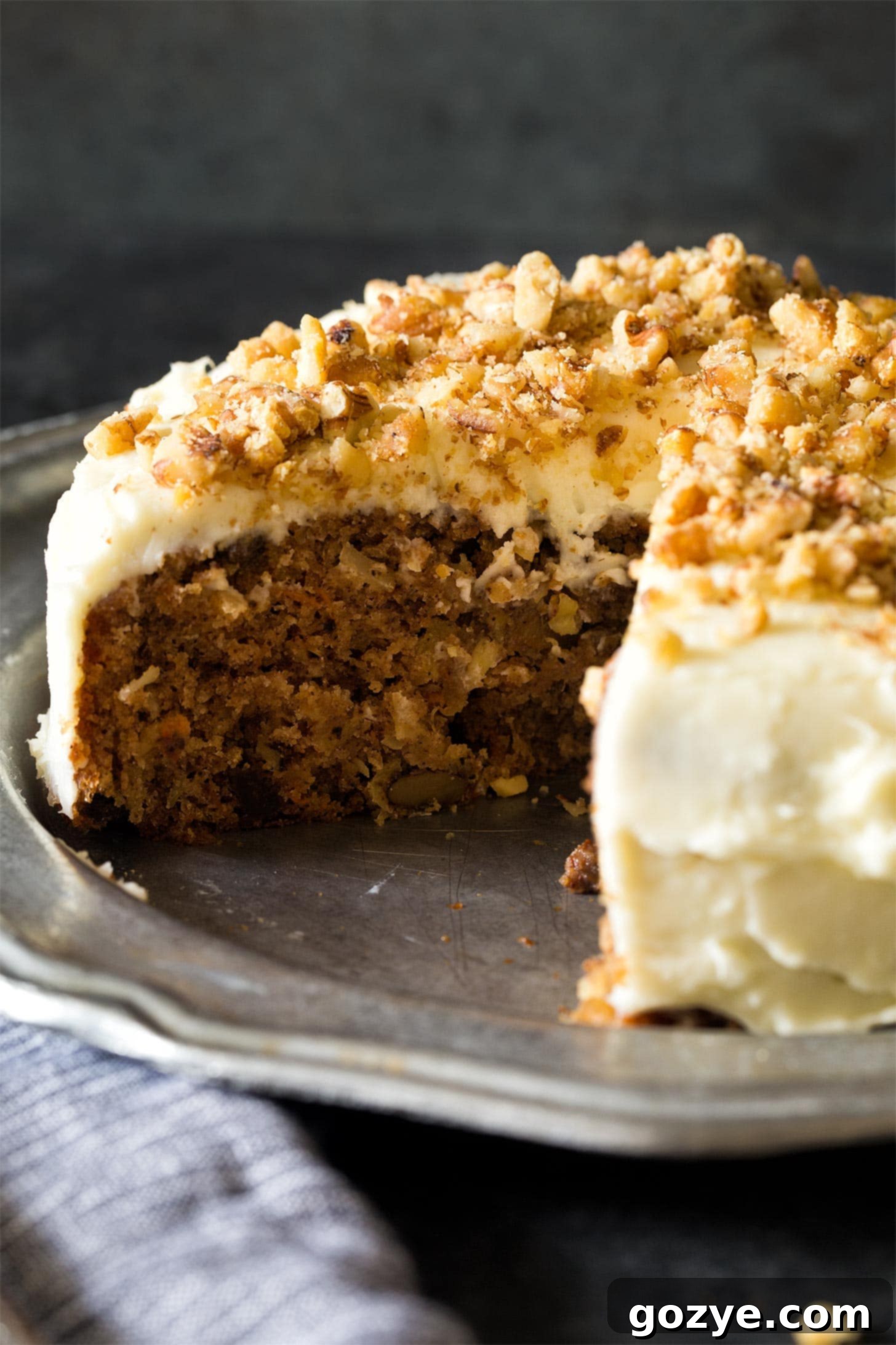 A small carrot cake adorned with beautiful cream cheese frosting, on a silver plate