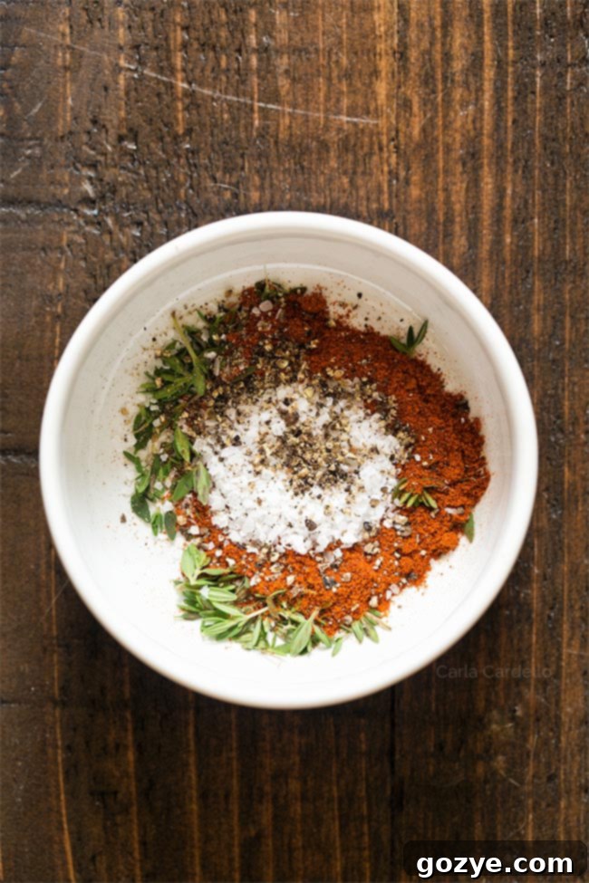 A bowl of seasoning blend for lamb chops, including thyme, paprika, salt, and pepper