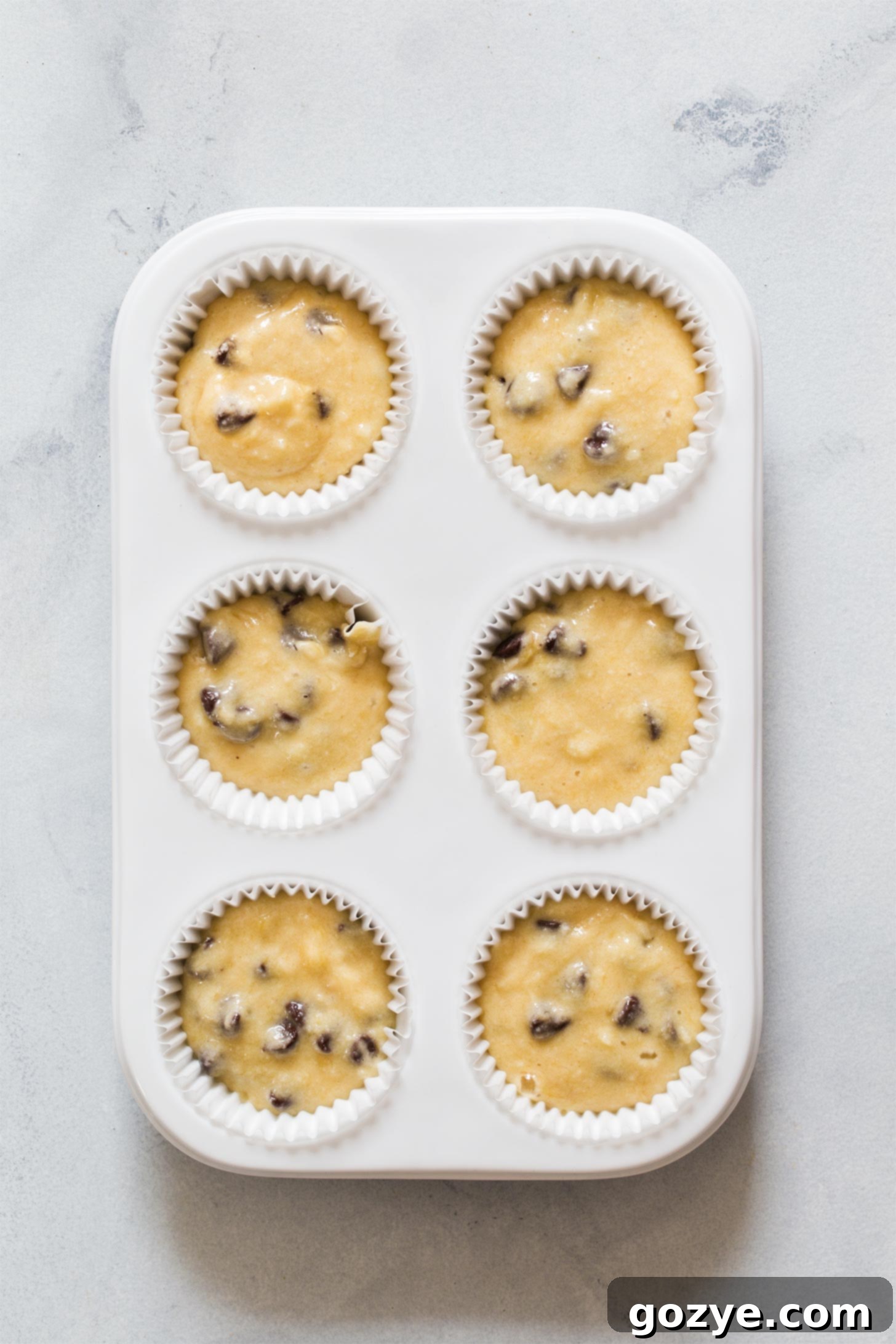 Paper liners filled with muffin batter, ready for baking