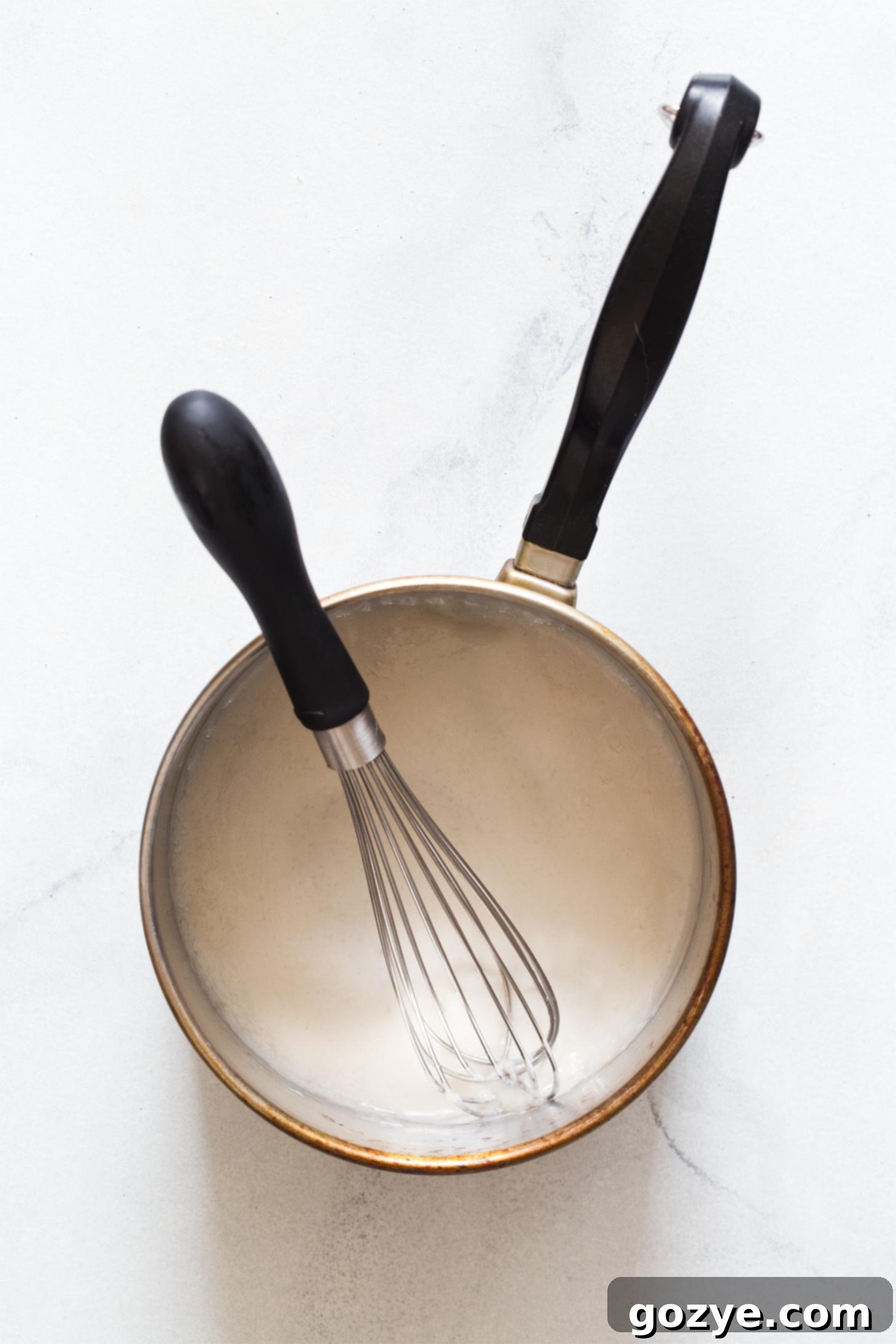 Whisking coconut milk and flour in a small saucepan for frosting base