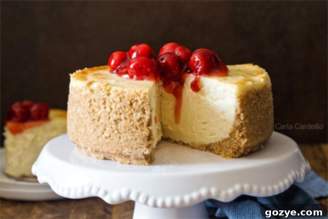 A small 6 inch cheesecake recipe garnished with cherry pie filling and a single cherry on top.