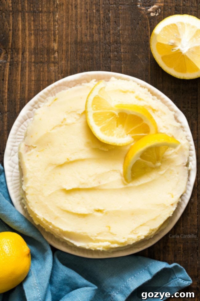 Slice of small cake frosted with lemon buttercream and adorned with fresh lemon slices