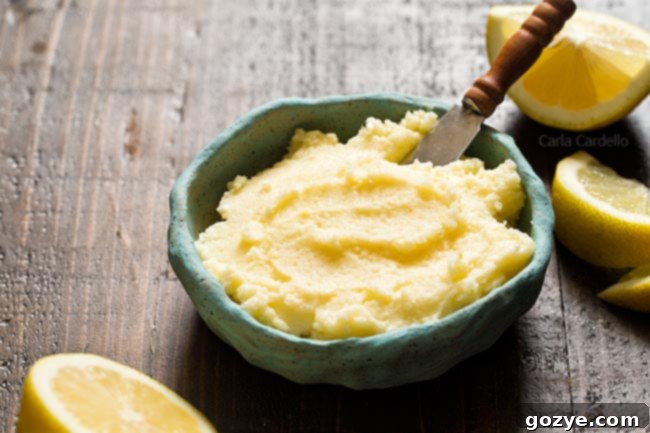 Another view of the blue bowl of Lemon Buttercream Frosting with a spoon