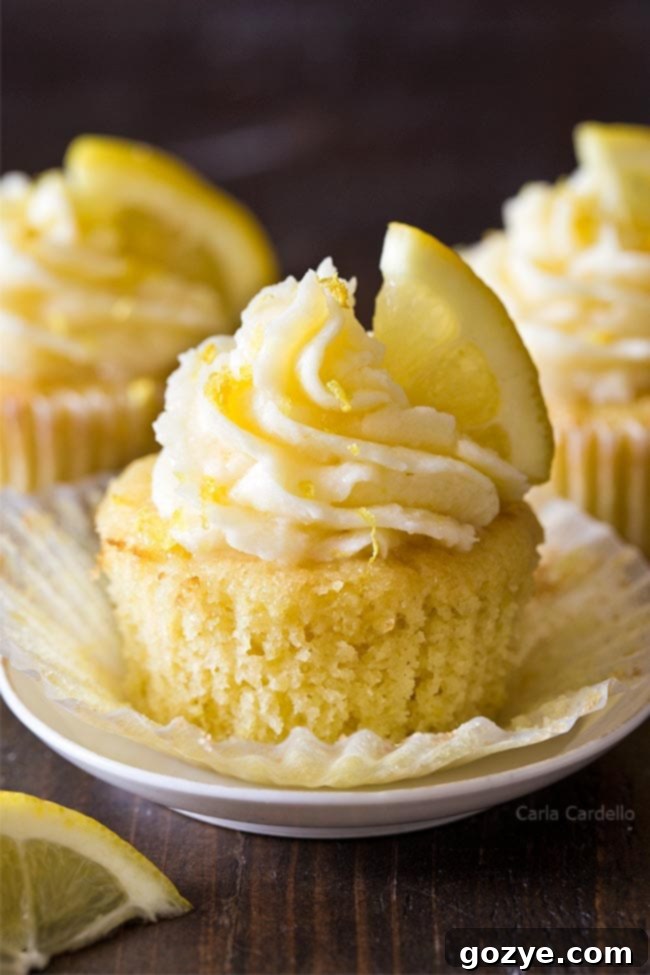 Easy Small Batch Lemon Cupcakes 2 Three perfectly frosted small batch lemon cupcakes on a white surface, garnished with lemon zest, exuding a vibrant and fresh appeal.