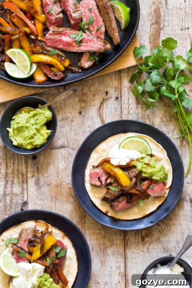Two plates of delicious Steak Fajitas served in corn tortillas with fresh toppings