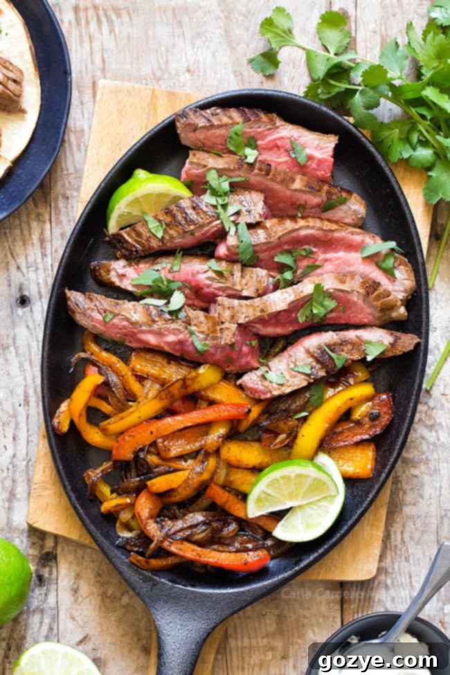 Close up view of marinated steak and vibrant bell peppers sizzling in a cast iron pan