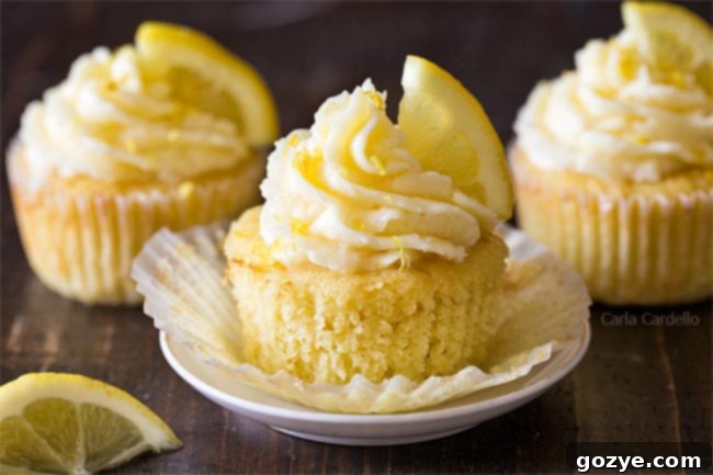 Bright yellow Lemon Cupcakes with swirls of lemon buttercream frosting and a delicate flower decoration