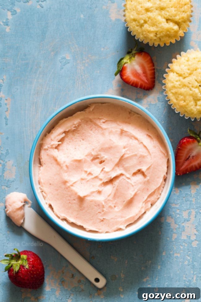 Vibrant pink small batch strawberry frosting in a white bowl, showcasing its smooth and creamy texture, ready to be used.