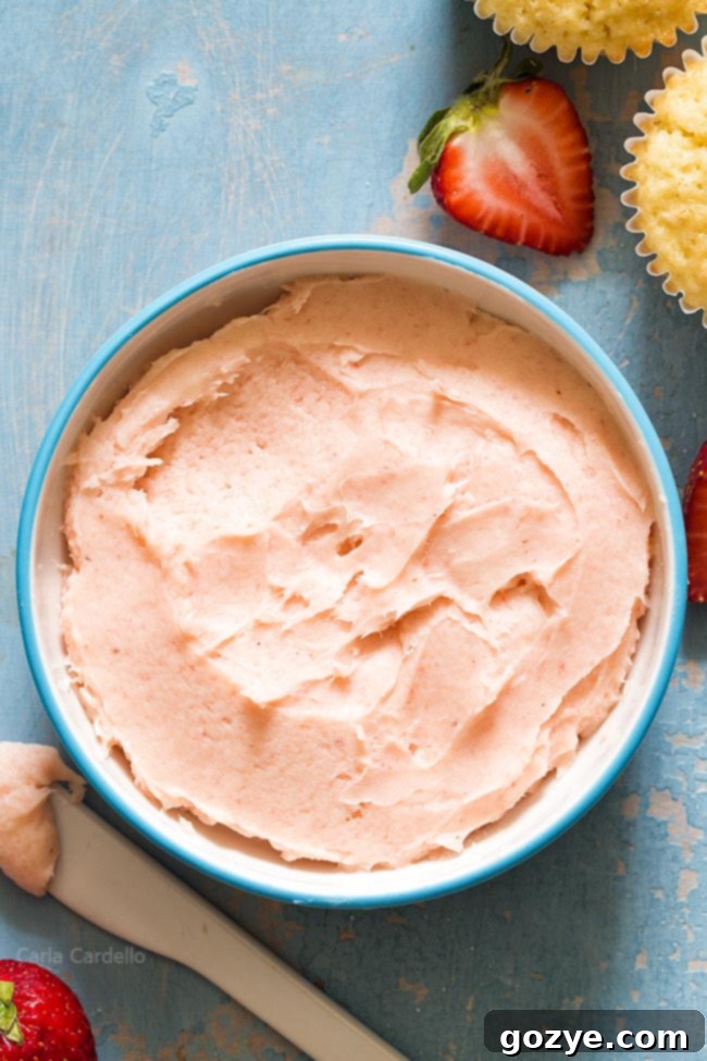 Close-up of the textured, creamy surface of fresh strawberry buttercream, highlighting its natural pink hue.