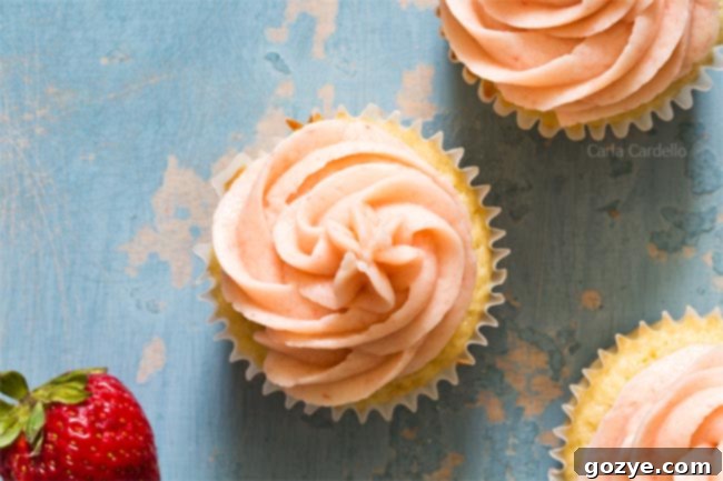 A perfectly piped swirl of pink strawberry buttercream on top of a cupcake, ready to be enjoyed.