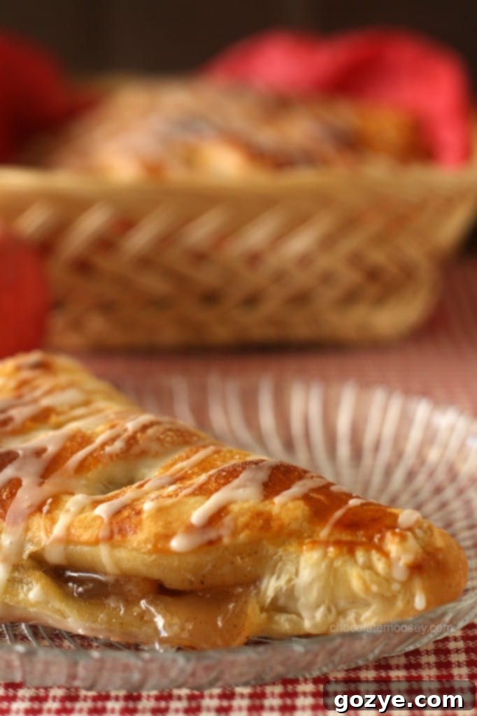 Close up shot of a golden-brown apple turnover, sprinkled with powdered sugar