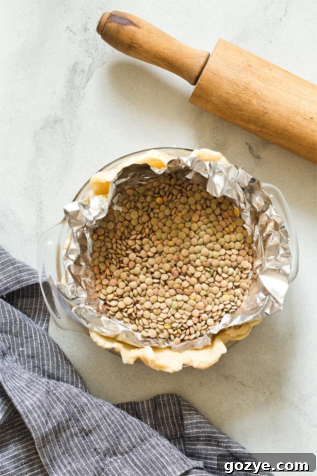 Unbaked pie crust filled with pie weights (dried lentils) for blind baking