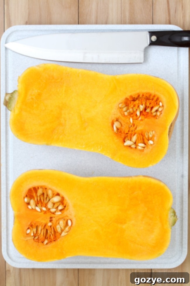 Savory Stuffed Butternut Squash 5 A butternut squash cut in half lengthwise on a cutting board next to a sharp knife.