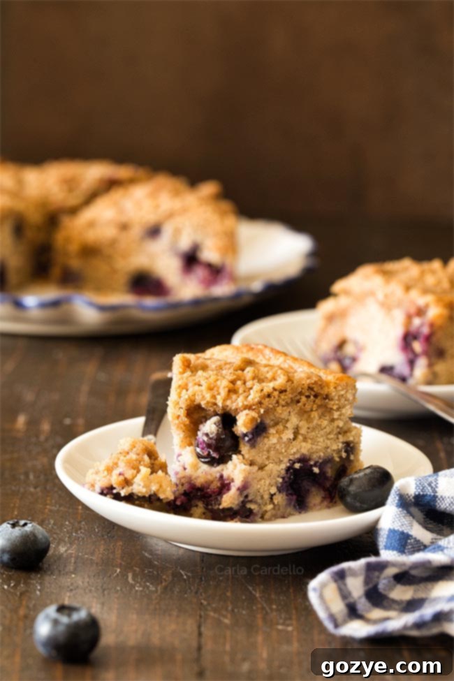 A delicious slice of small blueberry coffee cake with a bite taken, highlighting the moist interior and visible blueberries