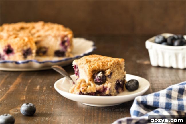 A delicious slice of small blueberry coffee cake with a bite taken, ready for enjoyment