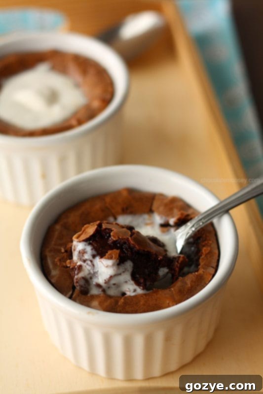 Fudgy brownie baked in a white ramekin, with a spoon digging into the center.
