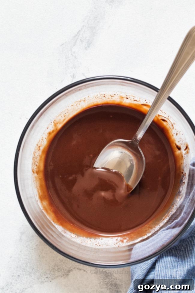 Glass bowl filled with luscious homemade chocolate ganache, ready to pour over desserts