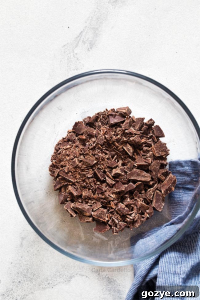 Finely chopped high-quality chocolate in a clear glass bowl, ready for ganache preparation